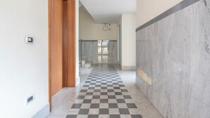Un pasillo con suelo a cuadros, una puerta de madera y paredes de mármol.