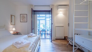 Habitación de hotel con cama, escritorio, silla, mesa y vistas al exterior.