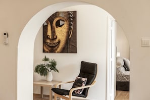 Una habitación con una silla moderna, una planta en maceta y una obra de arte colgada en la pared.