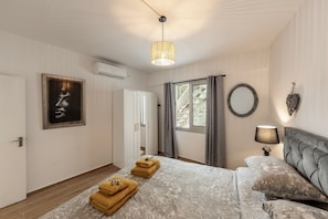 Un dormitorio con cama, lámpara colgante, espejo y puerta.