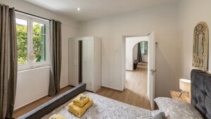 Un dormitorio con una cama, un armario, un espejo y una puerta que da a otra habitación.
