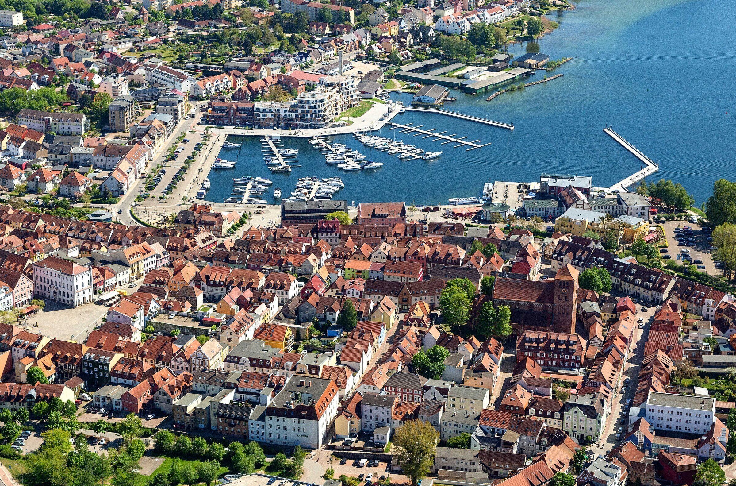 An aerial view of a town with a marina, historic buildings, and a river.