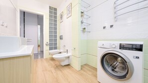 A modern bathroom with a bathtub, toilet, and washing machine. - Sun & Snow Port I (Kolobrzeg)