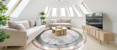 Una sala de estar moderna con sofá, mesa de centro, televisor y tragaluces.