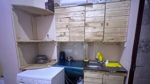 Cocina compacta con lavadora, lavaplatos y armarios de madera.