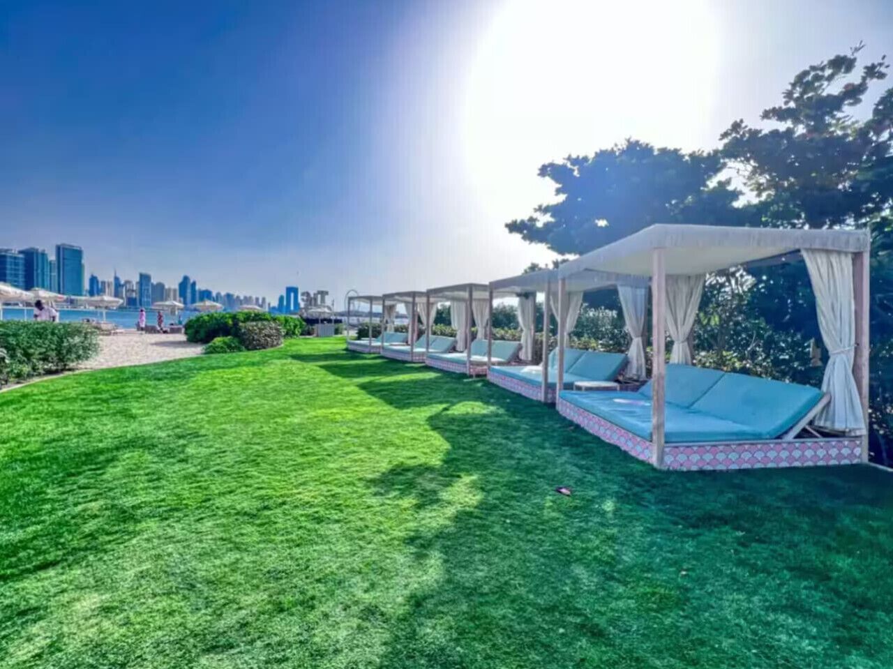 Un espace extérieur verdoyant, agrémenté d’une rangée de parasols et de chaises longues.
