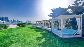 A grassy outdoor area with a row of canopies and lounge chairs. - FIRST CLASS | Studio | Palm Paradise (Dubai)