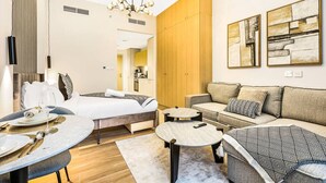 Una habitación de hotel moderna con cama, sofá, mesa de comedor y zona de cocina.