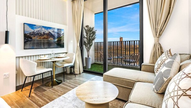Un salon moderne avec un canapé, une table à manger et des chaises. Une grande fenêtre, ornée de rideaux, offre une vue sur un paysage.