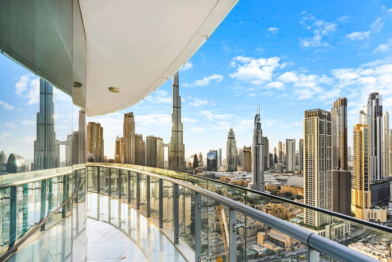 A high-rise building with a glass balcony overlooking a cityscape with numerous skyscrapers.