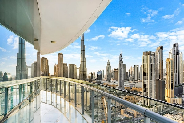 A high-rise building with a glass balcony overlooking a cityscape with numerous skyscrapers.
