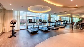 Una palestra moderna con diverse tapis roulant, ampie finestre e interni puliti e ben illuminati.