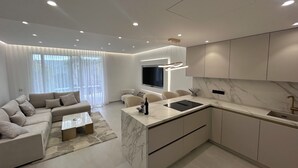 Een moderne keuken met een marmeren aanrechtblad, inbouwapparatuur en een flatscreen televisie.