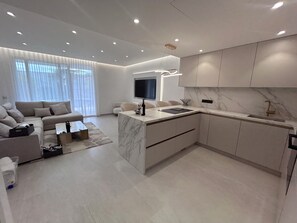 A modern kitchen with a marble countertop, integrated appliances, and a built-in TV.
