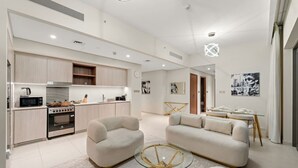 A modern living room with a sofa, a glass coffee table, and a kitchen area with a stove and microwave.