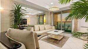 A modern living room with a beige sofa, a coffee table, and a large potted plant.