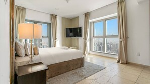 A modern hotel room with a large bed, a flat-screen TV, and a city view.