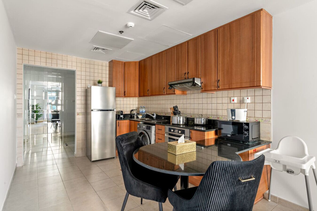 Una cocina moderna con armarios de madera, electrodomésticos de acero inoxidable y una mesa de comedor de vidrio con sillas.