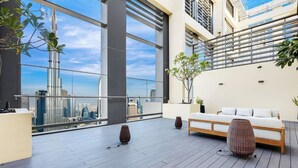 A modern rooftop terrace with a city skyline view, a sofa, and decorative vases.