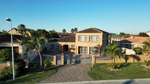 A two-story house with a brick facade, a tiled roof, and a gated driveway. - Sunset Events and Accommodation  (Gqeberha)