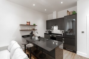 A modern kitchen with a central island, dark cabinetry, and a white countertop.