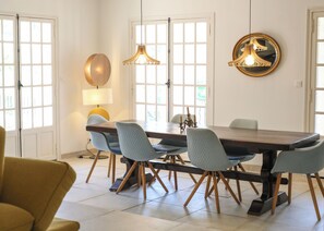 A dining area with a long table, six chairs, and pendant lighting.
