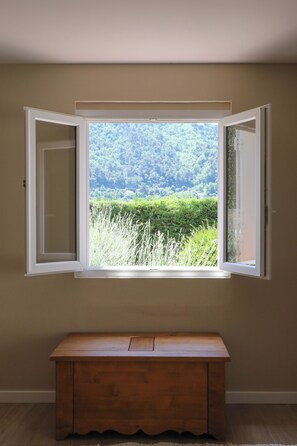 A room with a wooden bench and a window with open shutters.
