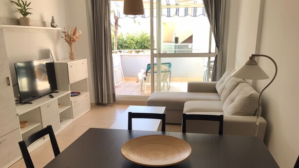 En moderne stue med fjernsyn, sofa, spisebord, stole og en lampe.