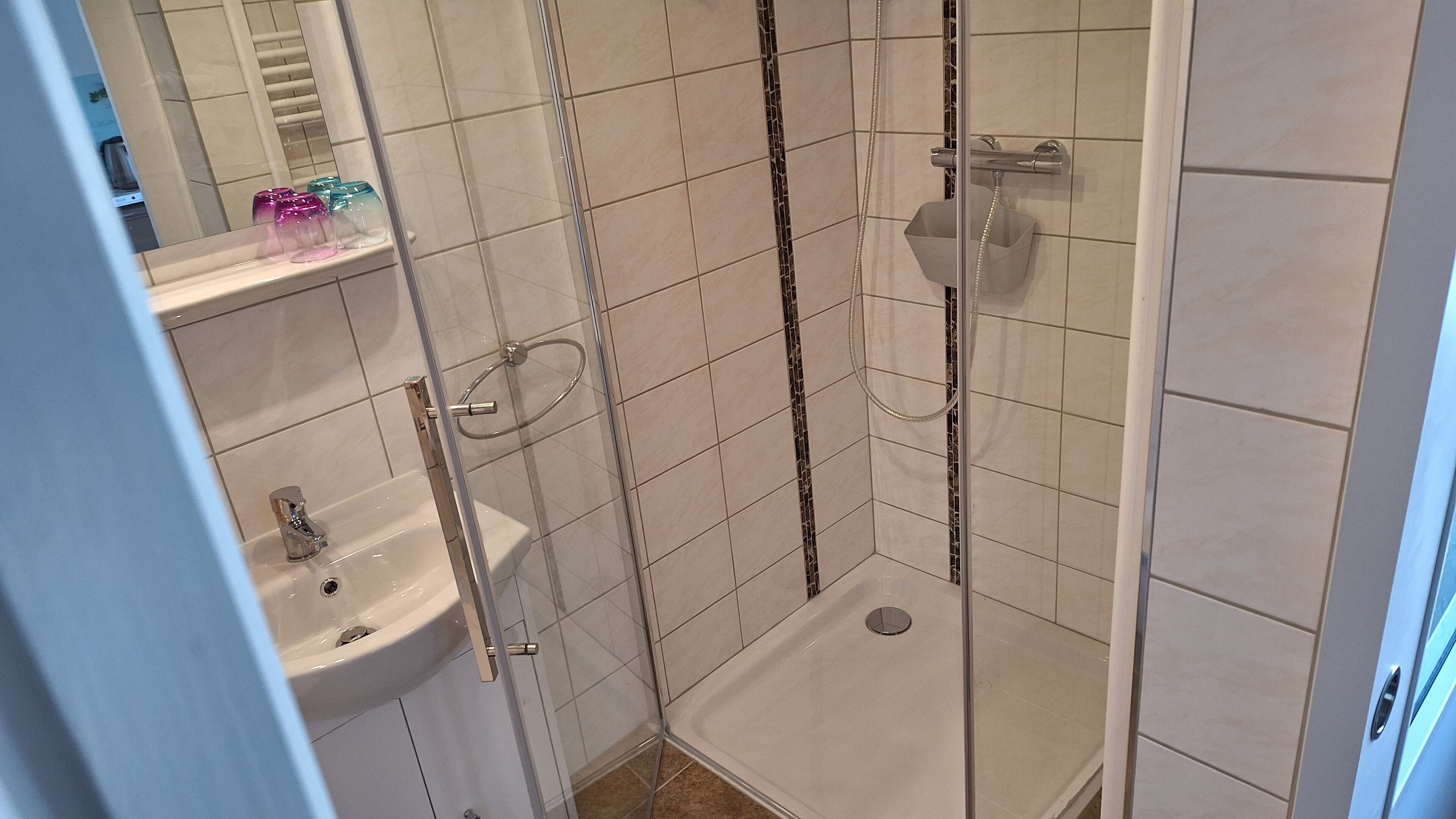 A bathroom with a glass-enclosed shower, a sink, and a toilet.