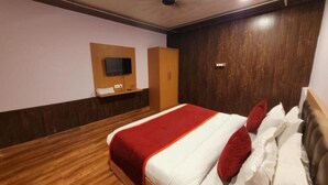 A bedroom with a bed, wooden wardrobe, and a mounted television. - Rang Vilas (Mathura)
