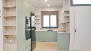 A kitchen with a built-in oven, microwave, and sink. There is a window above the sink and a door to the right.