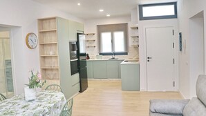 A modern kitchen with built-in appliances, a dining area with a table and chairs, and a living room with a sofa.