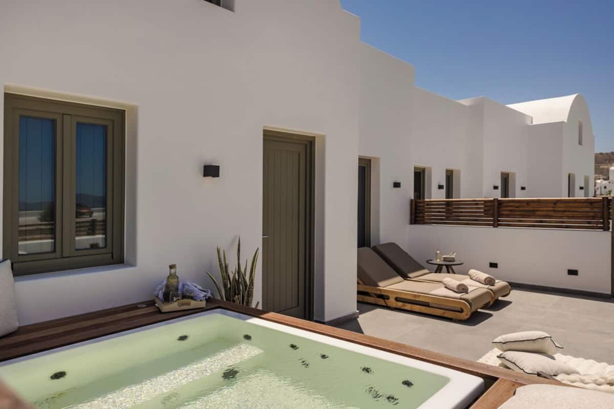 A rooftop terrace with a hot tub, lounge chairs, and a wooden deck.