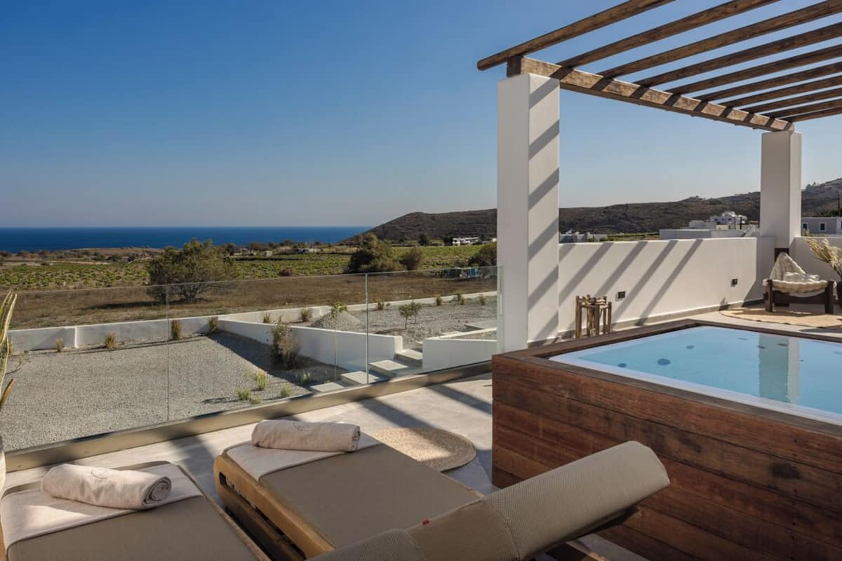 A rooftop terrace with a pool, lounge chairs, and a view of the sea.