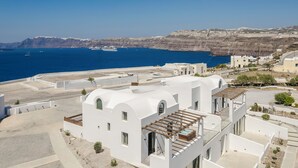 A coastal building with a white facade, a rooftop terrace, and a view of the sea and cliffs. - Acro Caldo Suites (Akrotiri)