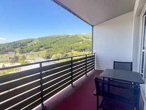 A balcony with a view of a green landscape and a building in the distance.