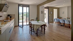 Une cuisine spacieuse avec un coin repas, une grande porte-fenêtre coulissante donnant sur un balcon et une vue sur l’extérieur.