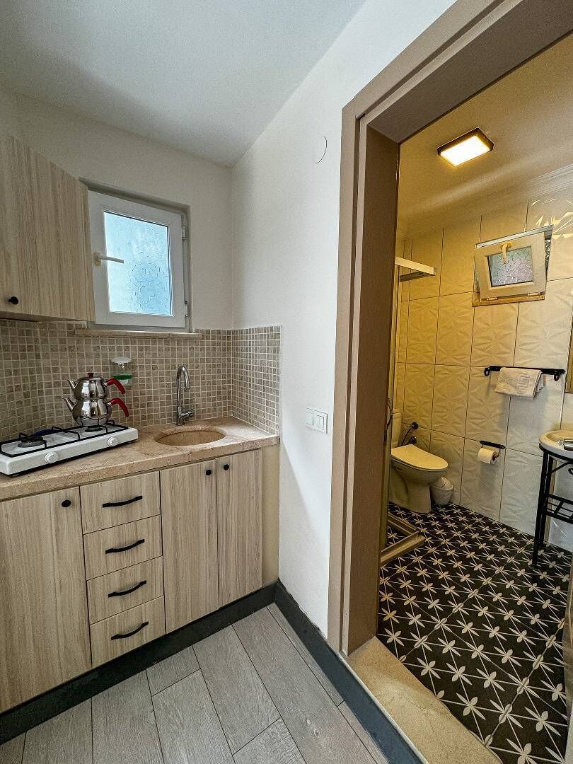 A compact kitchen with a gas stove, sink, and wooden cabinets.