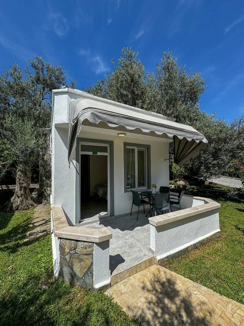 A small, modern outdoor structure with a covered patio area, stone steps, and a seating arrangement.