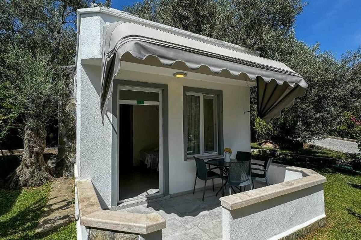 A small, modern outdoor structure with a covered patio area, stone steps, and a seating arrangement.