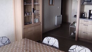 Una cucina compatta con forno a microonde, tostapane e pensili. C'è un tavolo da pranzo con sedie e un armadietto con vetri.