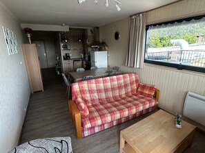 Un espace de vie compact comprenant un coin cuisine, un canapé, une table à manger et une fenêtre avec vue.