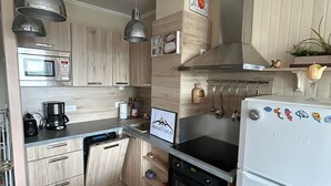 Una cucina moderna con mobili in legno, elettrodomestici in acciaio inossidabile e un appendiabiti per utensili.