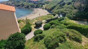 Une vue côtière avec une plage, un sentier et des bâtiments en arrière-plan.