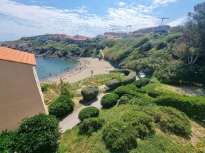 A coastal view with a beach, a path, and buildings in the background.