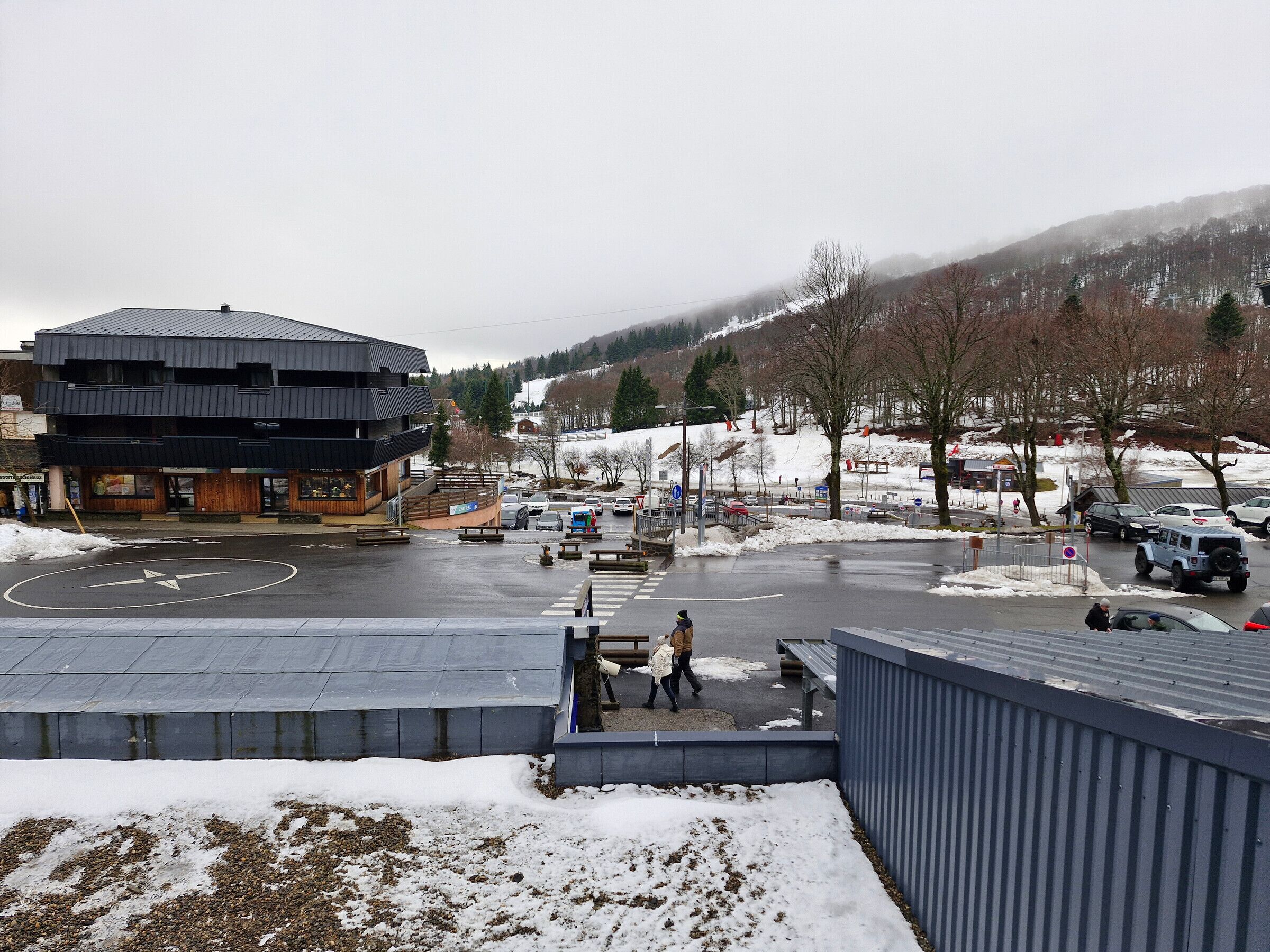 Un edificio moderno con techo plano y un estacionamiento cubierto de nieve.