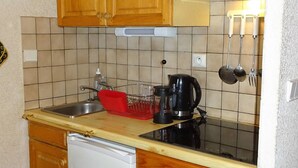 A compact kitchen with wooden cabinets, a stainless steel sink, a coffee maker, and a dish rack. - Les Gets: Charmant 2P+Coin Montagne, 5 Pers, Garage, Proche Centre et Pistes (Les Gets)