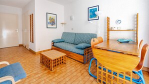 A compact living space with a sofa, a small wooden table, and a dining table with chairs. - Studio for 4 people with Wi-Fi, sea view (Roquebrune-Cap-Martin)