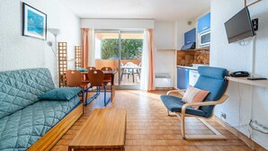 A cozy living area with a sofa, a dining table, and a chair. There is a kitchen area with cabinets and a TV. - Studio for 4 people with Wi-Fi, sea view (Roquebrune-Cap-Martin)