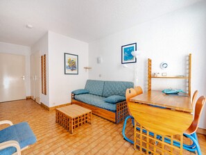 A compact living space with a sofa, a small wooden table, and a dining table with chairs.
